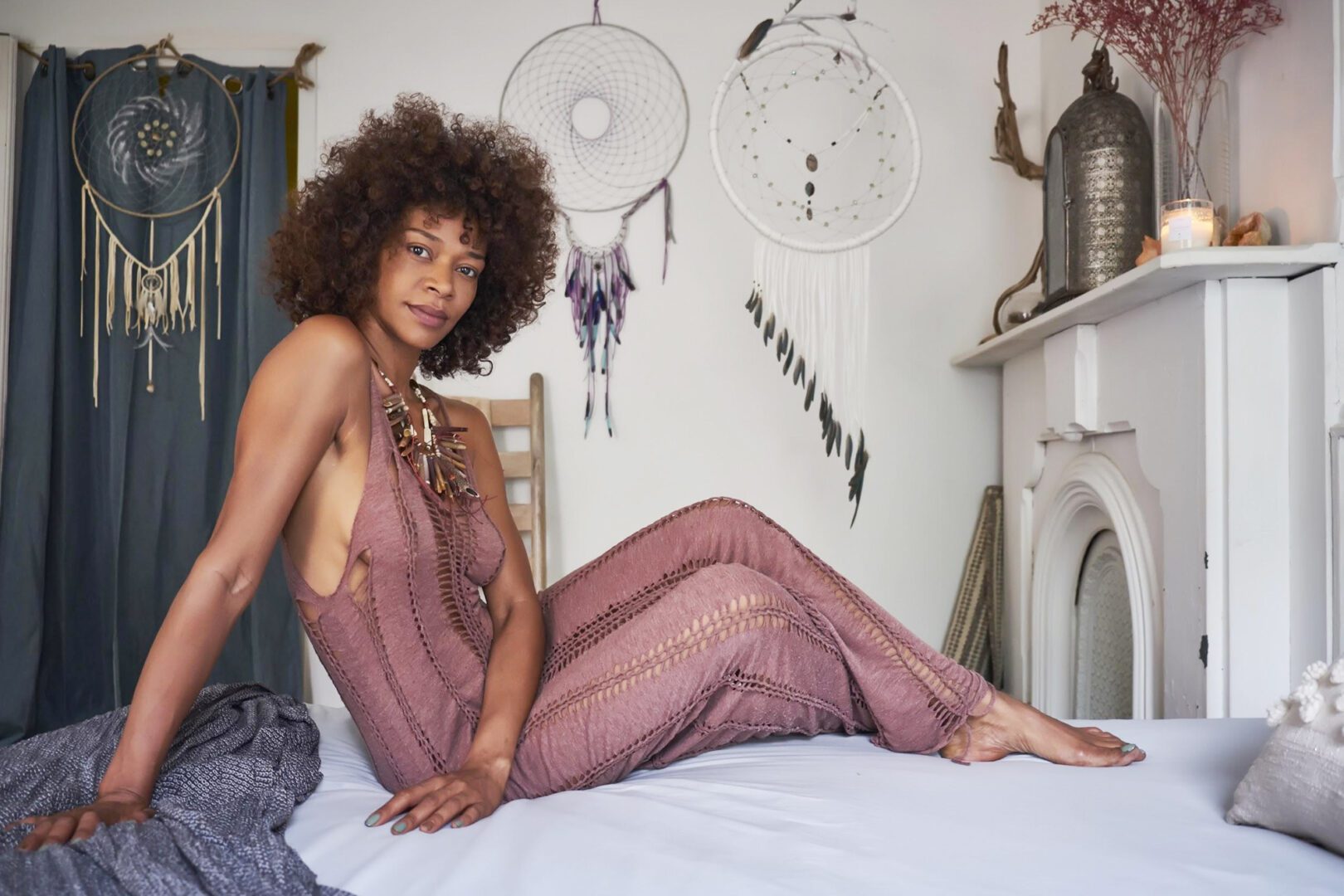 A woman in a pink dress sitting on the bed